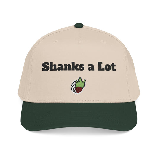 A structured baseball cap with a light beige crown and a dark forest green curved brim. The front of the cap features the text 'Shanks a Lot' in black, with a small embroidered green and red cartoon character below it.